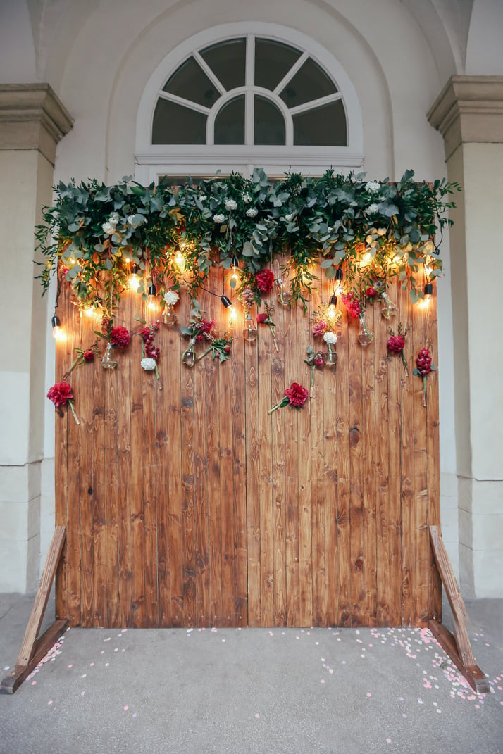 Rustic wedding photo zone. Hand made wedding decorations includes Photo Booth  red flowers. Garlands and light bulbs